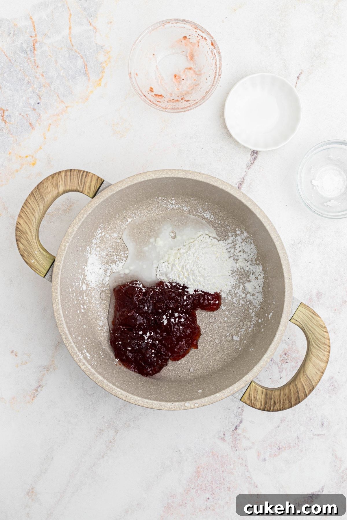 Cornstarch, water, and jam, being mixed together in a saucepan. 