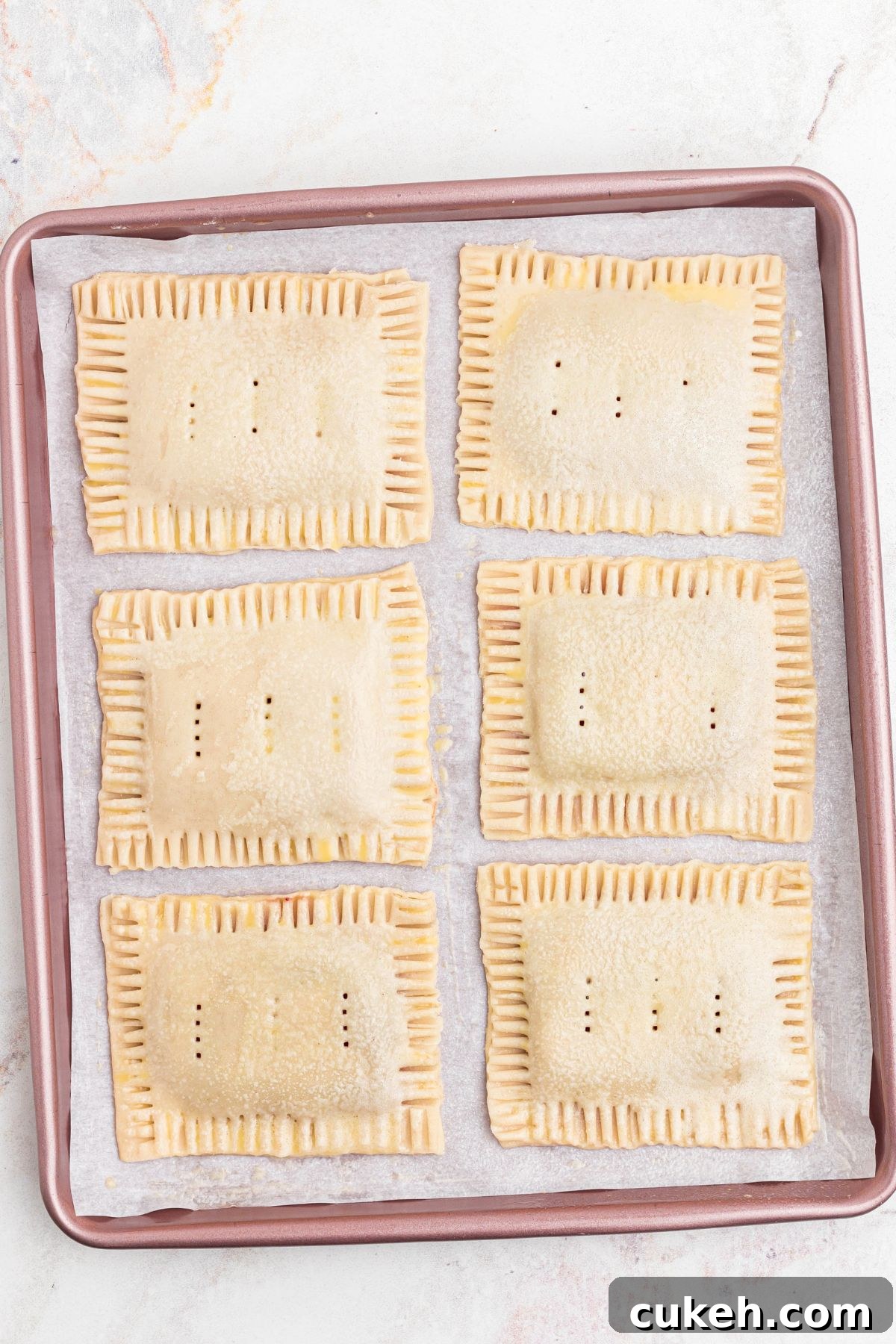 Pastries on a baking sheet, lined with parchment paper, before baking.