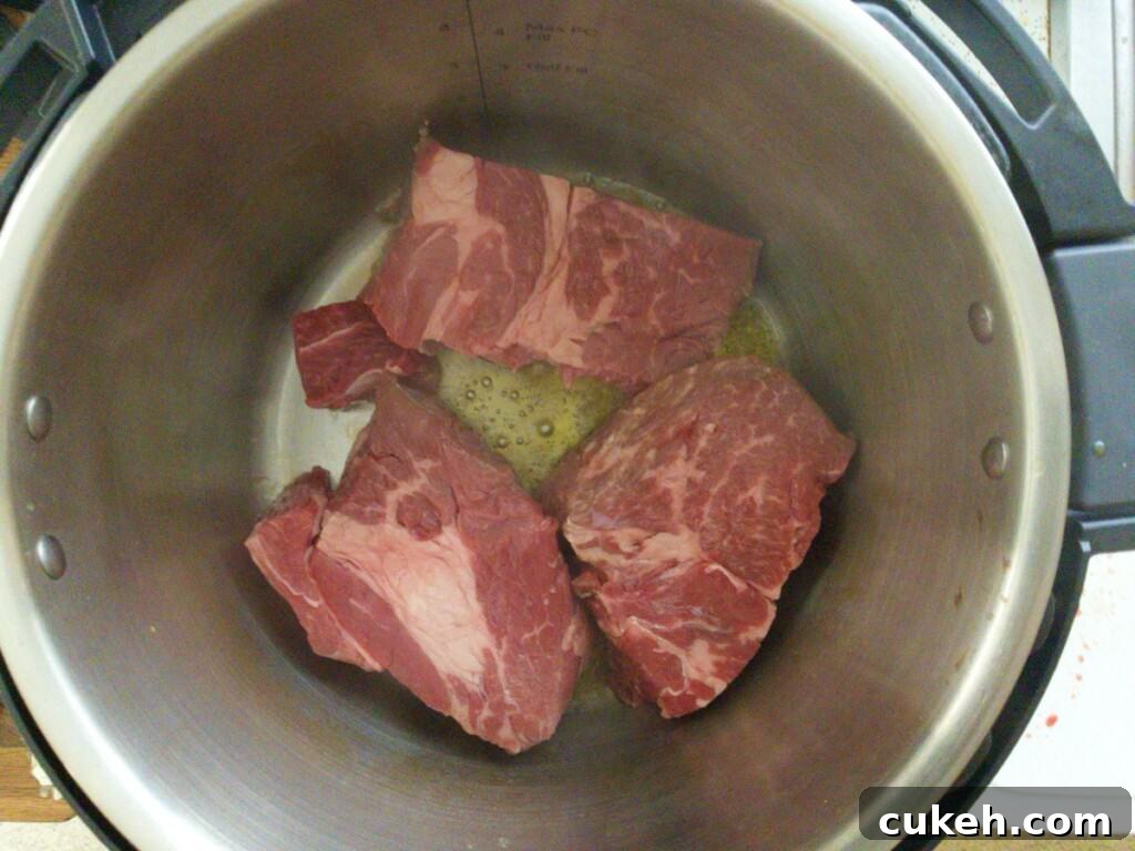 Pot roast in chunks being seared in instant pot for Mississippi pot roast. Step 2
