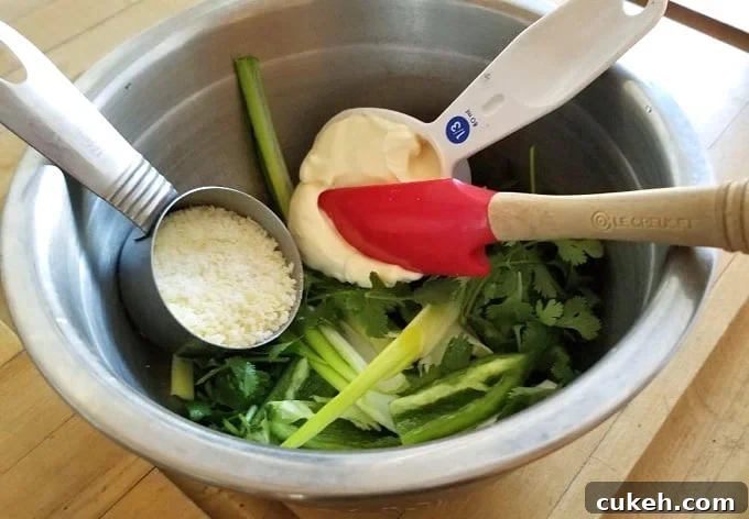 Peruvian ahi verde ingredients (cilantro, green onion, jalapeño, grated Parmesan cheese, light mayonnaise) in small bowl.