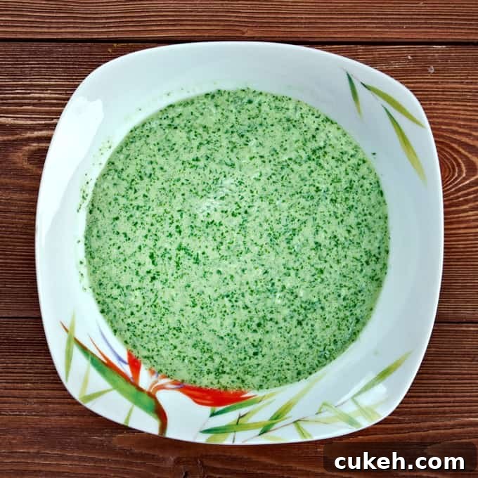 Spicy Peruvian aji verde in square white bowl on wooden table.