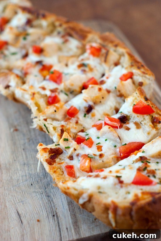 Split apart Garlic Bread Pizza with fresh tomatoes, mozzarella on a wooden board.