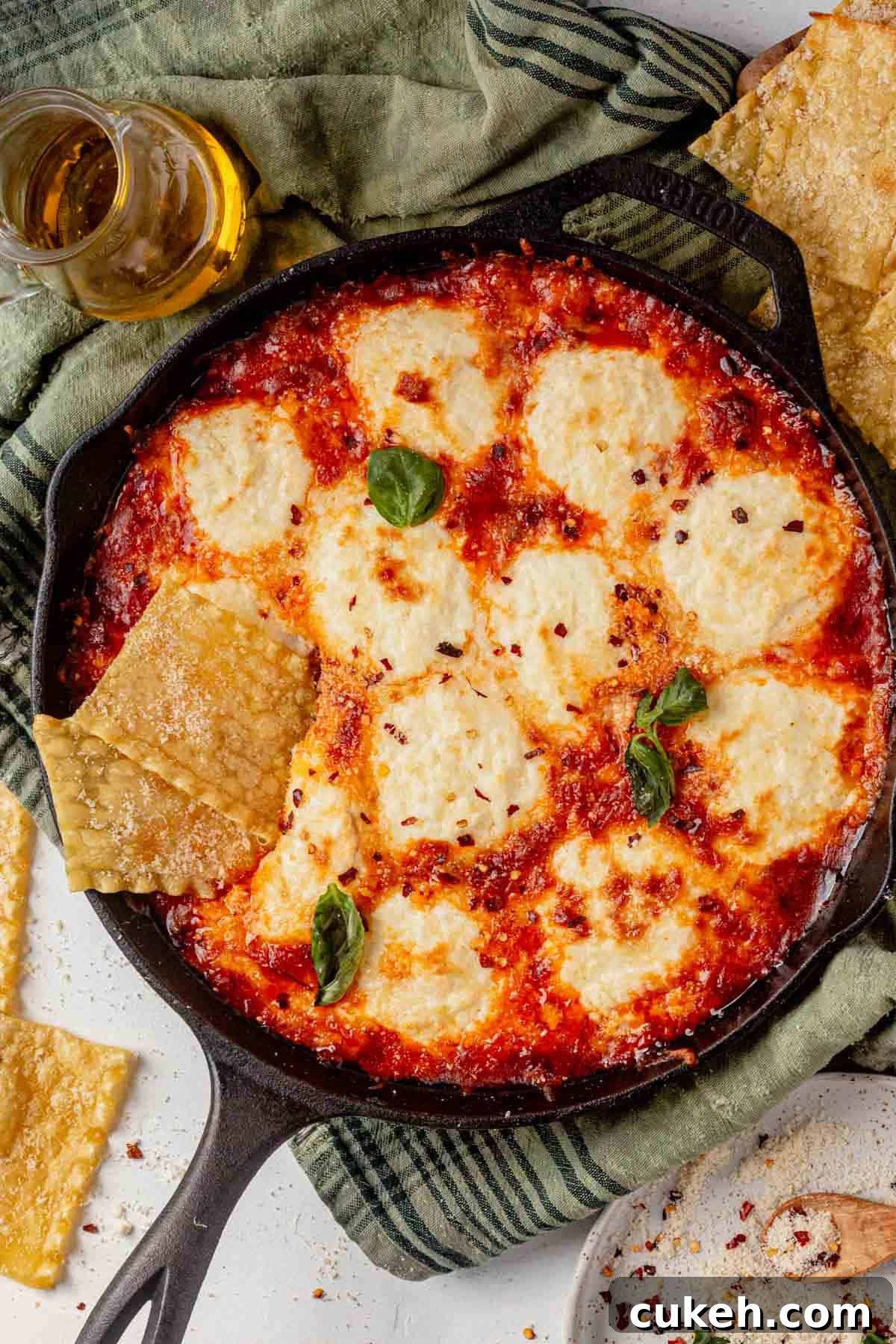 lasagna dip in a cast iron skillet with pasta chips and basil.