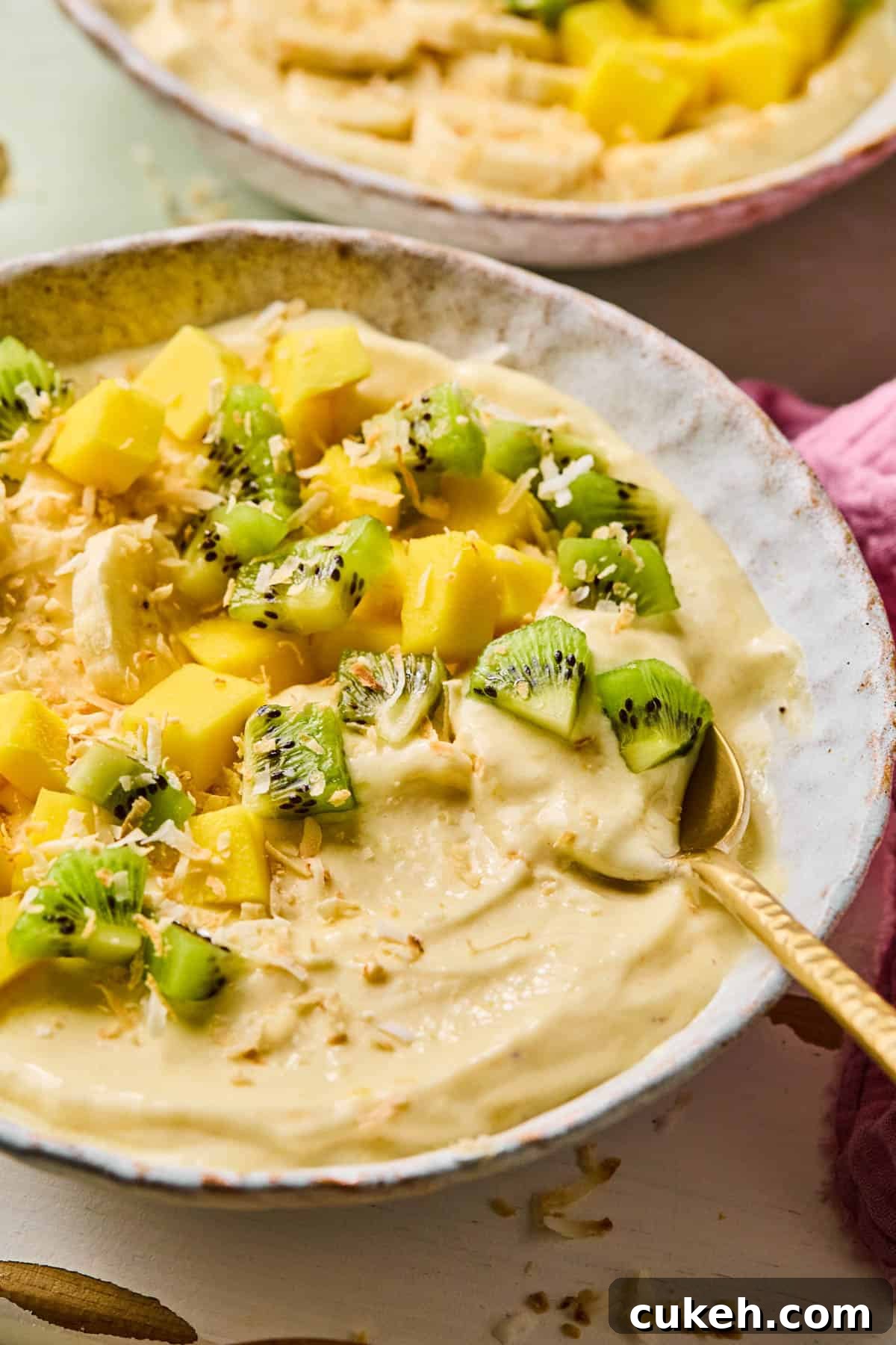 coconut smoothie bowl with all of the toppings and a spoon dipped into it