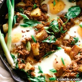 Pulled pork, potatoes and eggs in a cast iron skillet with scallions, fresh dill and red pepper flakes topped.