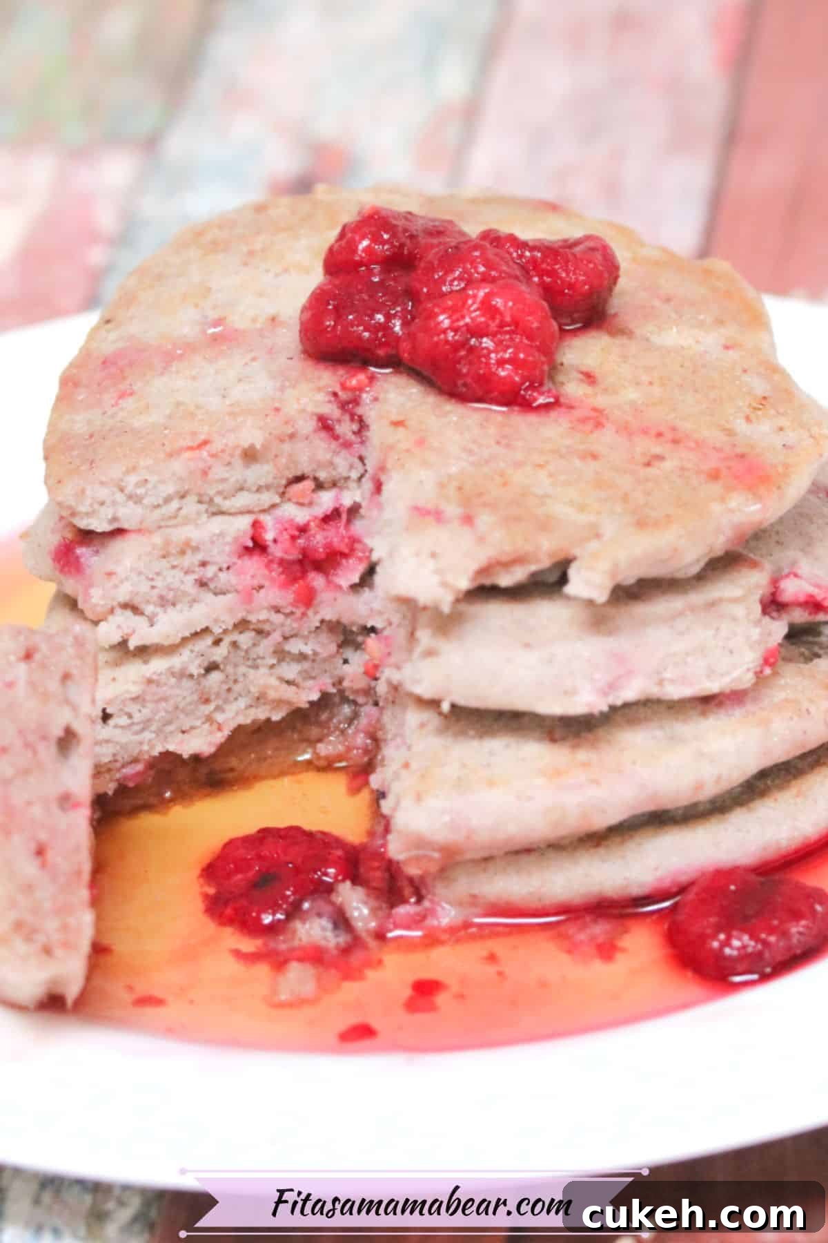 Is Buckwheat Gluten-Free? What You Should Know Before Eating It 3 Vegan buckwheat pancakes stacked on a white plate with raspberries on top and a forkful of pancake removed from the stack and on the side of the plate.