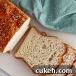 half sliced loaf of gluten free English muffin bread on white cutting board with teal cloth napkin.