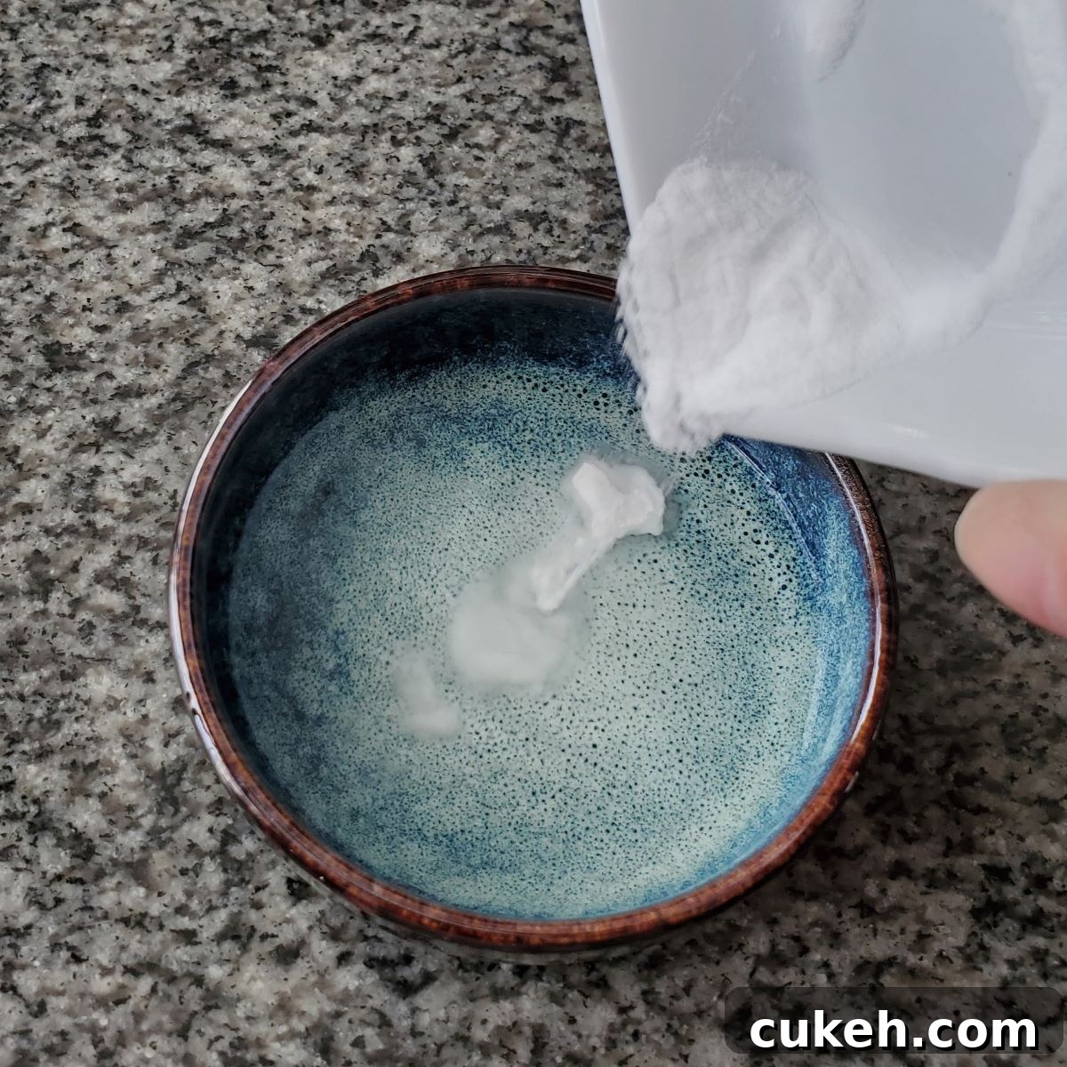 mixing baking soda into water in a small blue bowl.