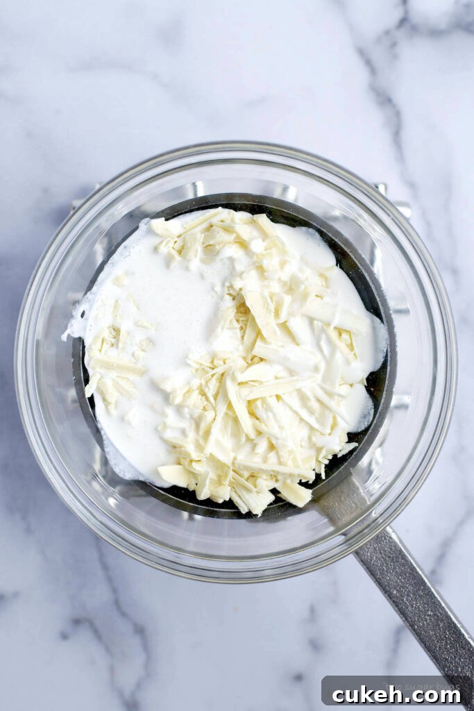 chopped white chocolate and heavy cream in a bowl over a saucepan