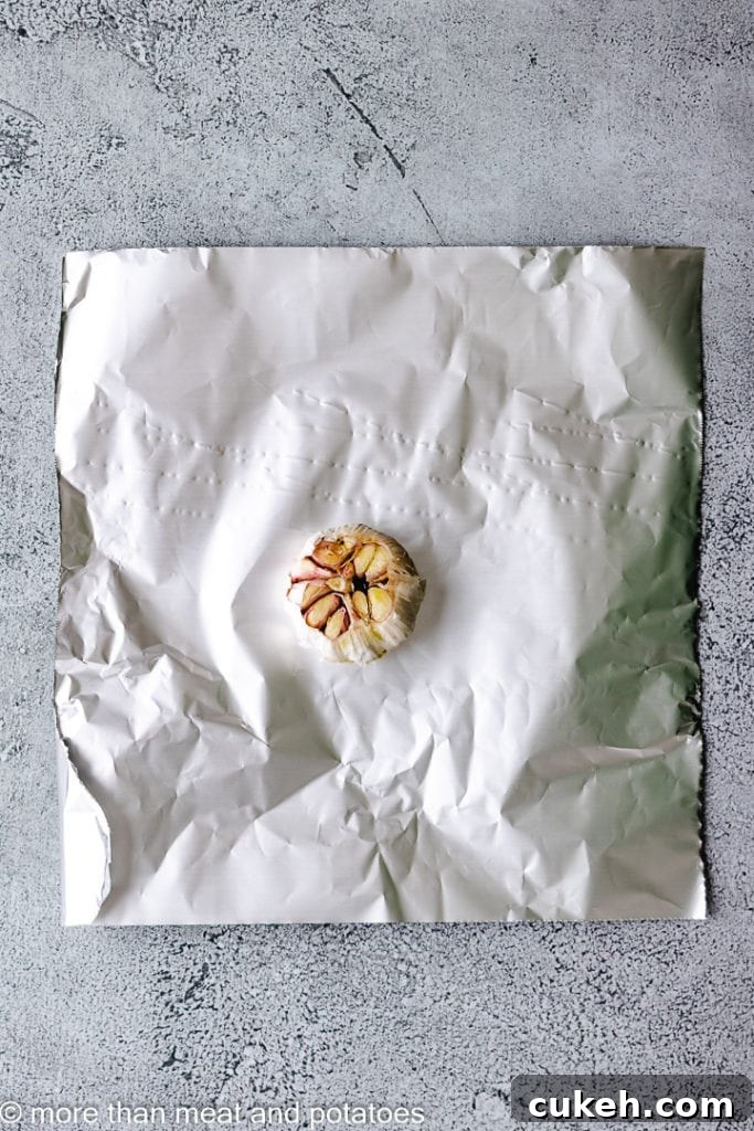 Bulb of garlic on a piece of aluminum foil.