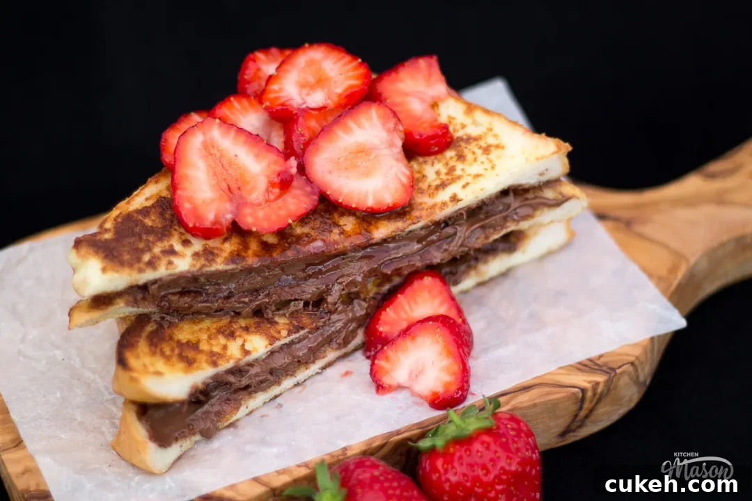 Strawberry Nutella French toast sliced in half on a chopping board.