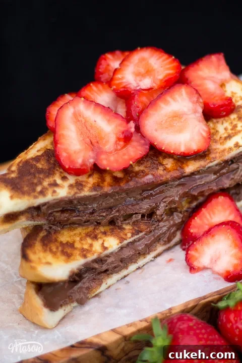 Sliced strawberry Nutella French toast on a board topped with macerated strawberries.