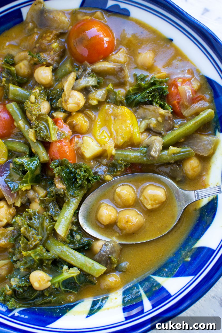 20-Minute Coconut Chickpea Curry with Spinach and Tomato 3 A closeup of a 20-minute coconut chickpea curry with a spoon in it