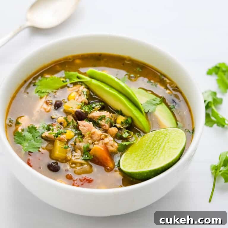 A bowl of chicken taco soup with lime for squeezing.