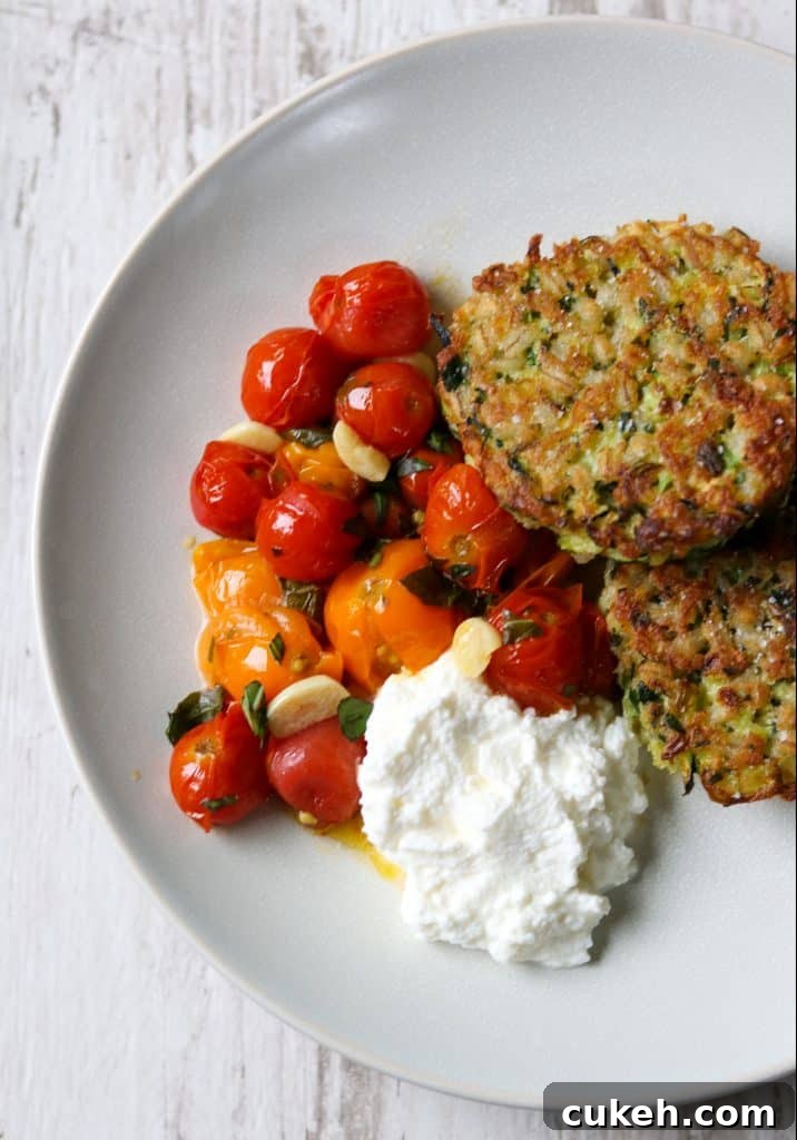 Zucchini and Barley Cakes with Roasted Cherry Tomatoes & Ricotta 2 Zucchini barley cakes, roasted cherry tomatoes and ricotta cheese on a a plate