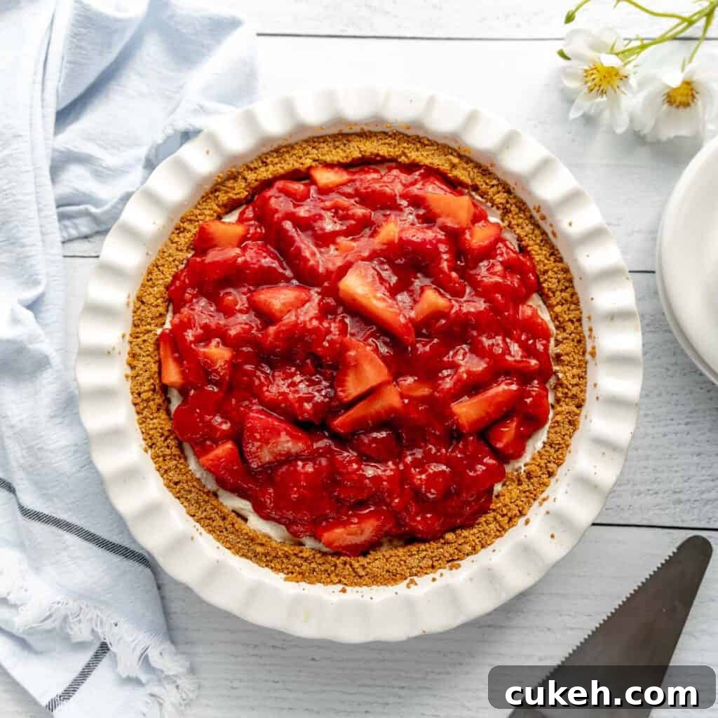 Strawberry pie with a pie server and flowers around.