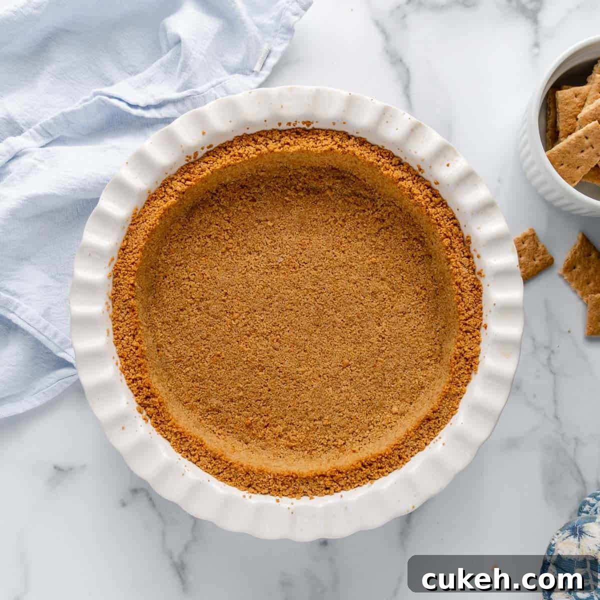 Overhead of a graham cracker crust in a white pie plate.