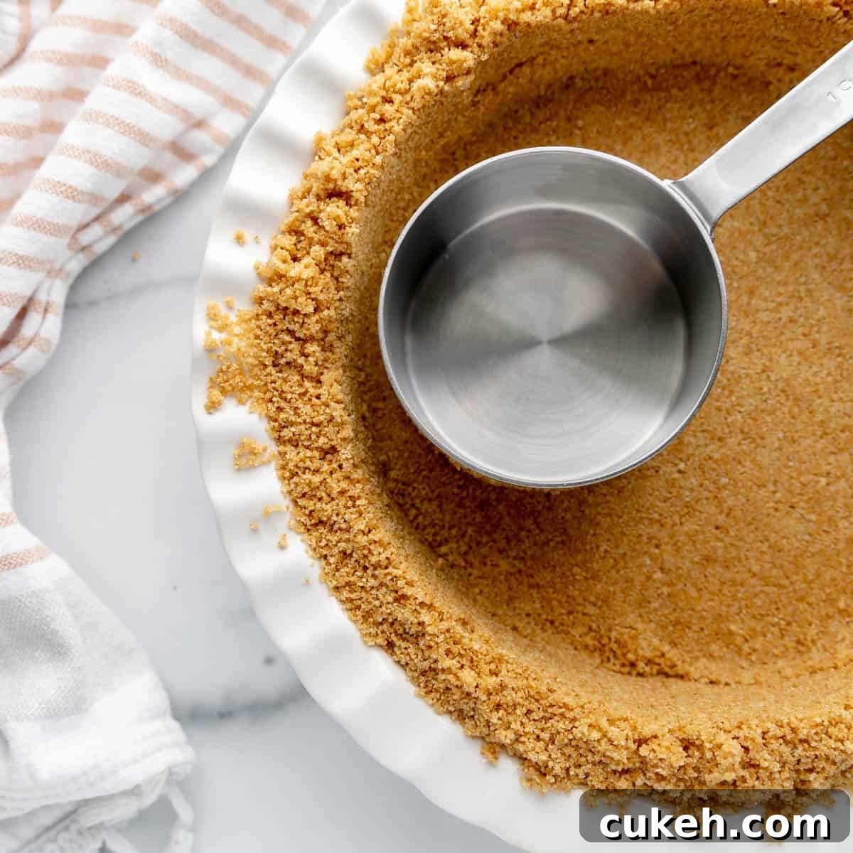 A measuring cup in a pie plate with graham crackers.
