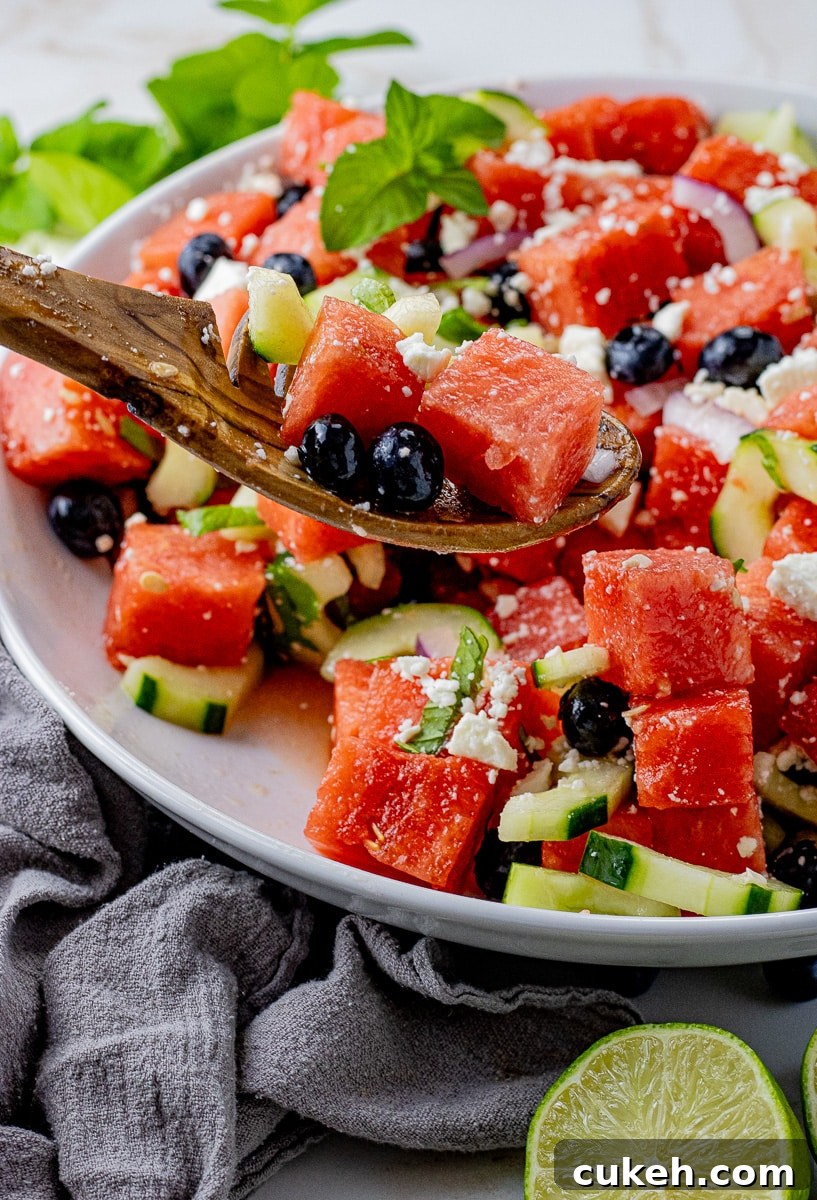 Refreshing Watermelon and Feta Salad with Mint and Balsamic 2 wooden spoon scooping up cubed watermelon with blueberries and feta cheese