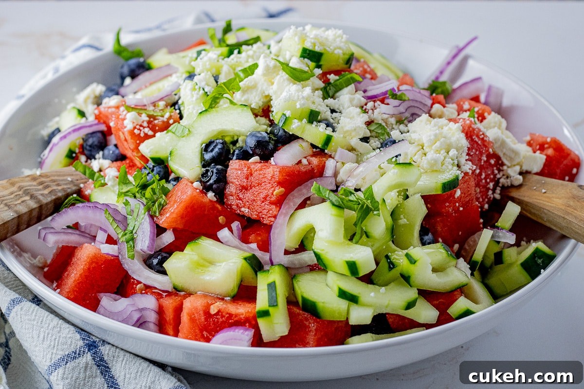 Refreshing Watermelon and Feta Salad with Mint and Balsamic 3 sliced cucumbers, red onions, watermelon and feta cheese in a large white bowl