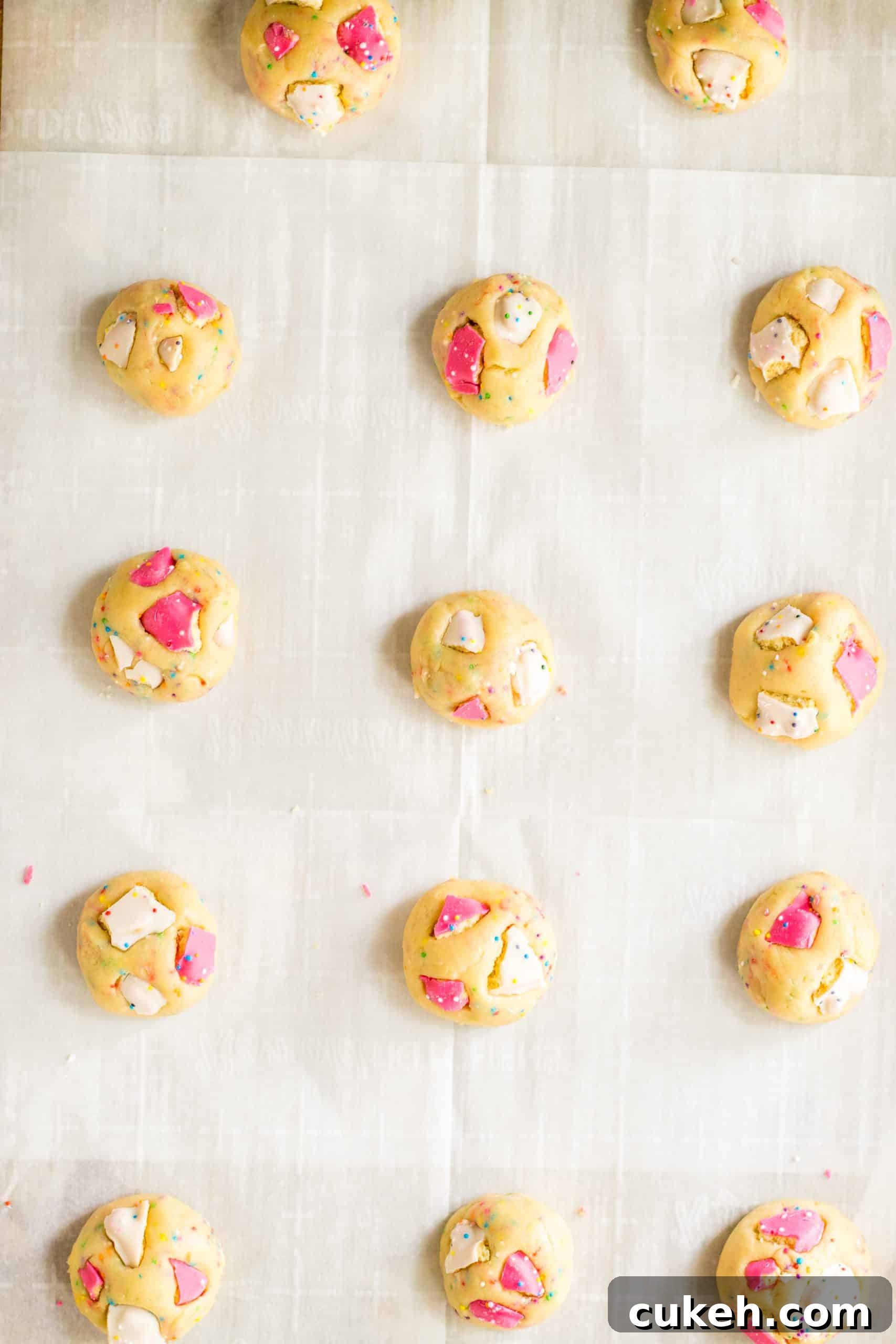 circus animal cookie dough balls arranged in rows on a parchment paper lined baking sheet
