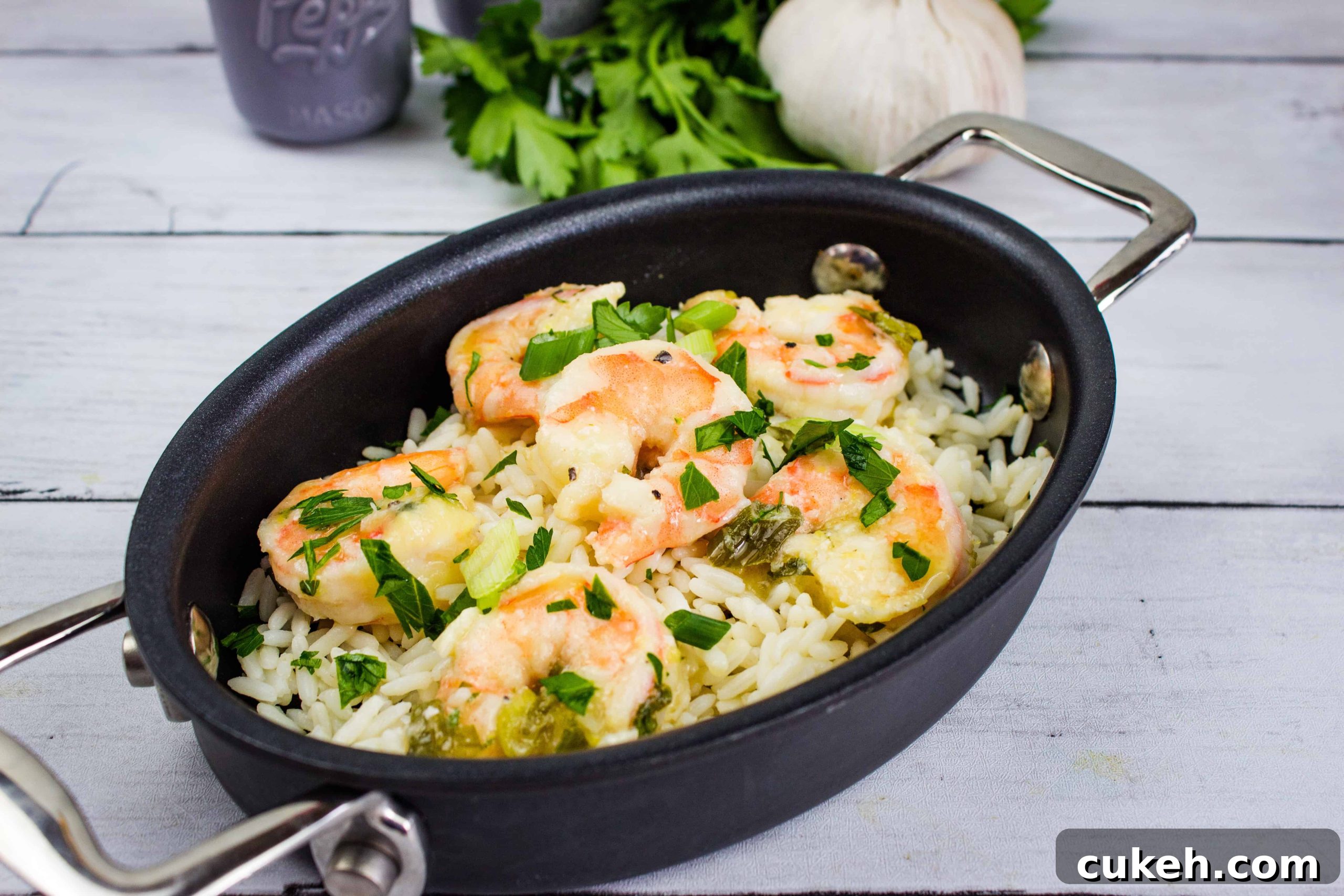 Fresh shrimp with rice, herbs, and vegetables in a black cooking skillet. Perfect for quick, flavorful meals.