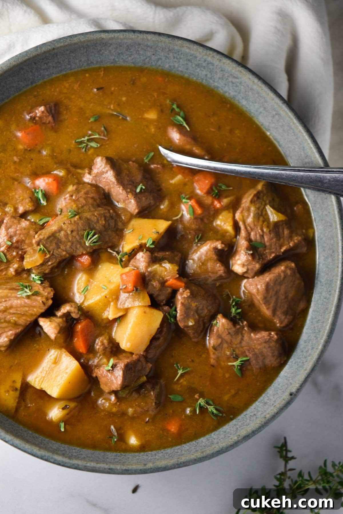 A bowl of beef stew with carrots and potatoes on a kitchen towel