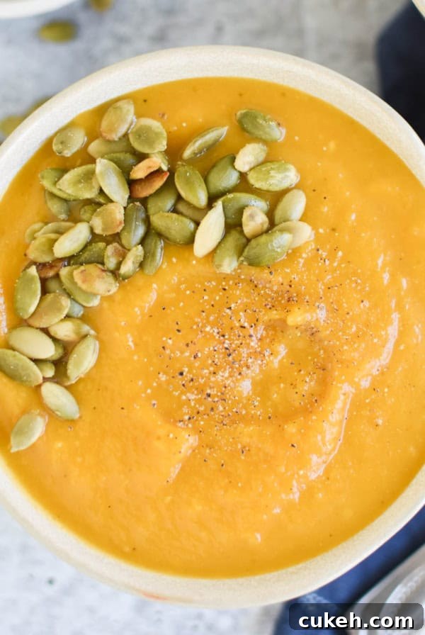 A bowl of butternut squash soup next to a spoon.