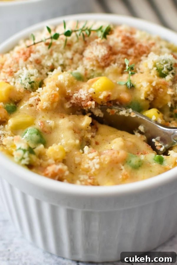 A spoon dipping into a white ramekin with crustless chicken pot pie.