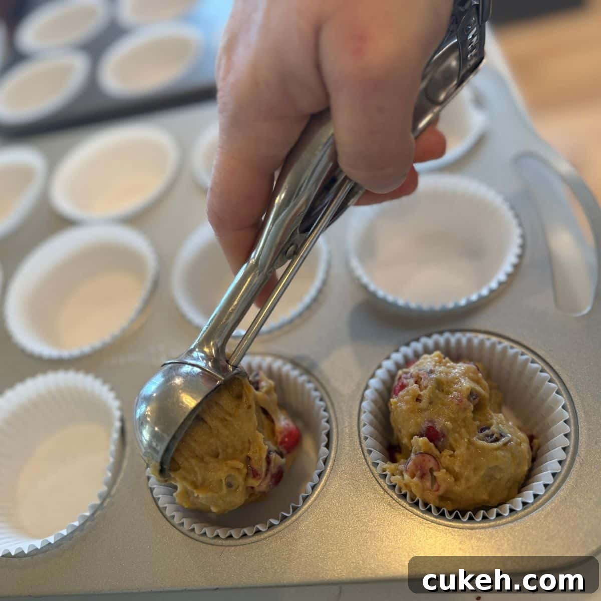 filling muffin tins with cranberry orange batter