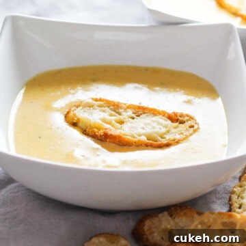 White bowl filled with cheese soup and a homemade crouton on top.