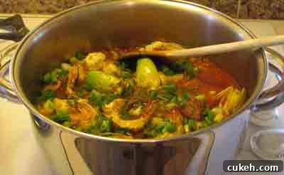 Adding the artichokes, scallions and dill to beef with artichokes moschari-me-agkinares