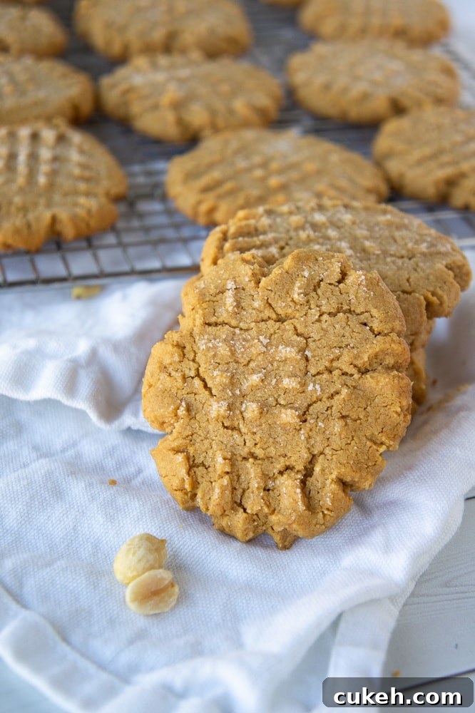 a stack of flourless peanut butter cookies in front of a cooling rack of cookies