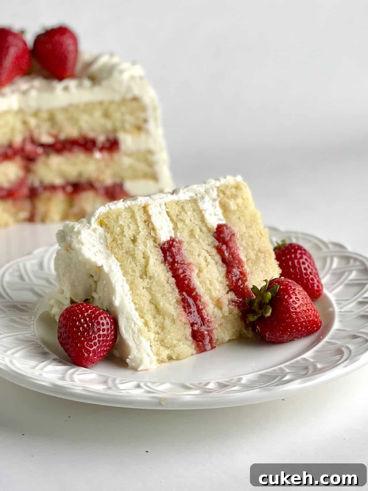 A slice of cake with Strawberry Cake Filling flavor and the rest of the cake in the background.