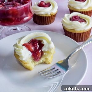 A closeup of a vanilla cupcake filled with cherry filling