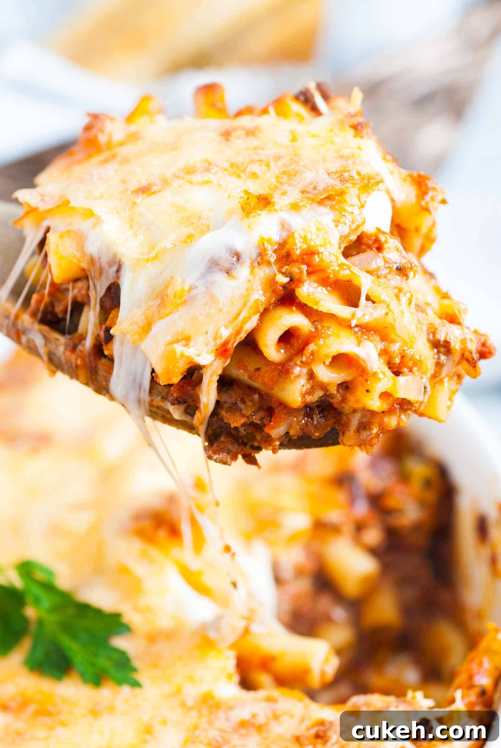 Spatula scooping baked pasta from a pan.