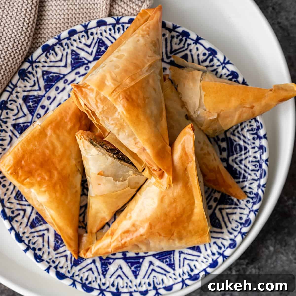 overhead: greek spanakopita triangles on blue and white plate