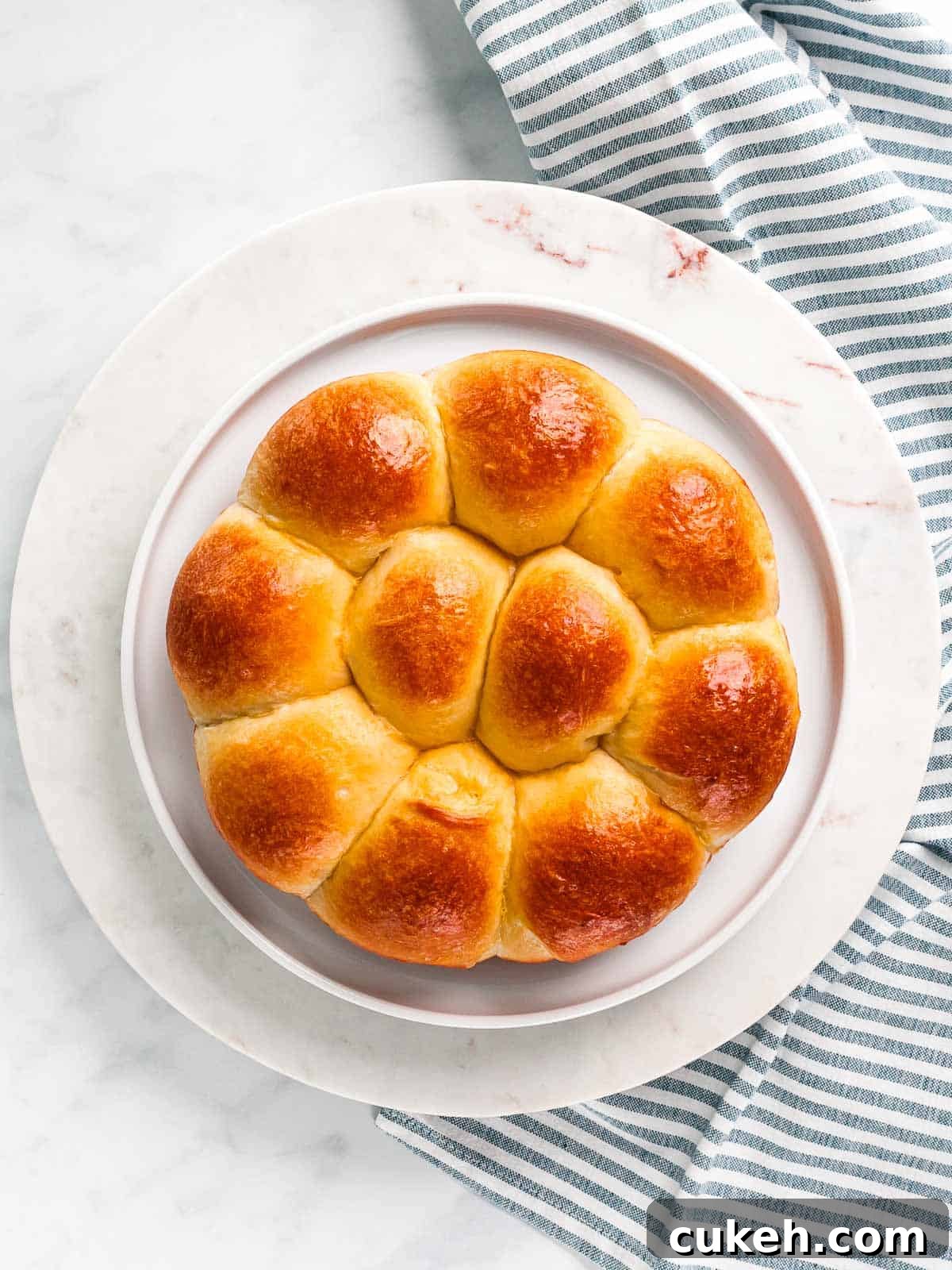 Buttery brioche rolls baked in a round pan on a white plate.