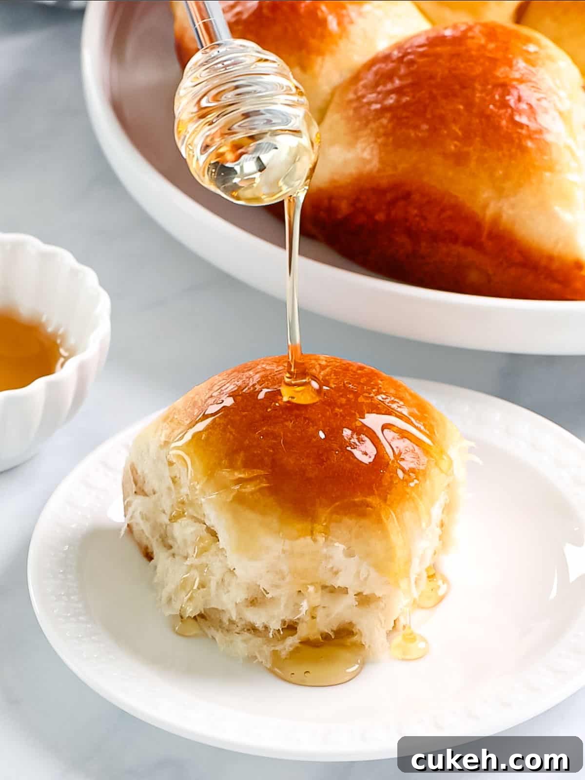 Buttery brioche rolls being drizzled with honey.