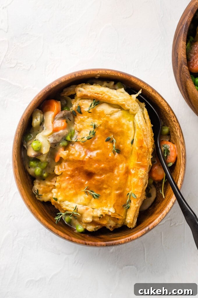 Fennel & Potato Vegetable Pot Pie Recipe — Savory Comfort Dish 9 Small wooden bowl with a serving of vegetarian pot pie with a puff pastry crust.